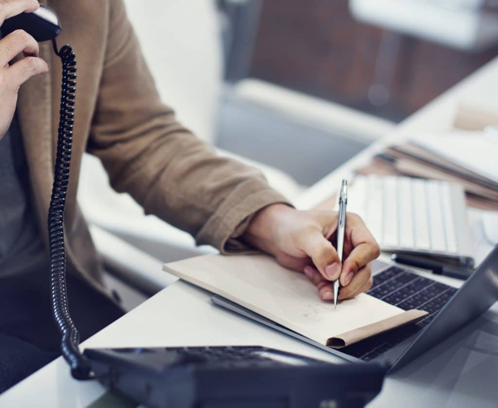 Homme au téléphone qui écrit une note